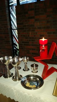 Abendmahlsgeräte, Kelche und Patene auf dem Altar mit einer Kerze 