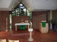 Blick in den Kirchraum am St. Johannes Gemeindezentrum, Altar mit dem grünen Parament der Trinitatiszeit, Taufkerze lionks und Taufständer in der Mitte sowie dem Lesepult an der rechten Bildseite.