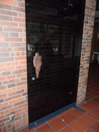 Glastür mit großem unregelmäßig geformten Türgriff aus einem Bombensplitter