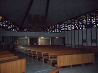 Innenansicht der Kriche Allerheiligen Buntglasfenster über hellen Kirchenbänken
