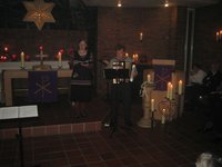 Kirchenraum mit zahlreichen brennenden Kerzen, leuchtender Weihnachtsstern, Ulrike Klank mit Textheft in der Hand, Holger Jablonowski hinter einem Notenständer mit Akkordeon im vorweihnachtlichen Abend. 