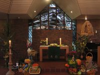 Altarraum im St. Johannes Haus, üppiger Erntedankschmuck, brennende Kerzen, Erntekrone 