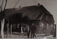 Bauernhaus mit Ziegeldach, gekalktem Obstbaum, Erwachsener und Kind vor dem Gartenzaun 1924