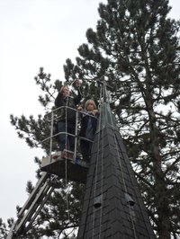Spitze des Glockenturms von St. Johannes Hasport-Annenheide mit Hubsteiger daran und Pfarrerin Ulrike Klank mit Harald Siemund bei der Installation von Lichterketten.