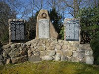Denkmal für die Toten der letzten Kriege, viertelkreisförmige  Feldsteinmauer mit schwaren Steintafeln, in die die Namen der Toten eingraviert sind.