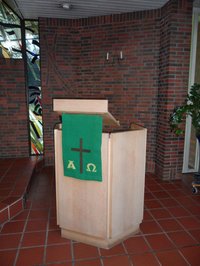Lesepult mit Antependium, schmückender Behang aus grünem Stoff, Alpha und Omega und Kreuz