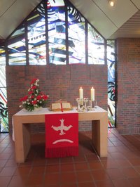 Altar im St. Johannes Haus mit dem roten Altartuch zu Pfingsten - die herabkommende Taube steht für den Geist Gottes
