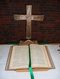 Das Altarkreuz der St. Johannesgemeinde mit der aufgeschlagenen Altarbibel. 