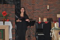 Solosängerin in der Kirche St. Johannes zwischen geschmücktem Altar und brennenden Kerzen auf dem Klavier