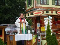 Pfarrer Guido Wachtel der Röm.-kath. Pfarrei St. Marien Delmenhorst im Gebet hinter dem Altar, im Hintergrund ein Verkaufswagen für Popkorn und Zuckerwatte.
