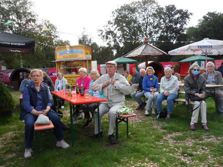 Menschen auf Bierzeltgarnituren nehmen am open-air Gottesdienst auf dem "Markt" Sommerwiese in Delmenhorst teil. 13.9.2020