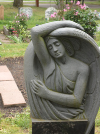 Engelfigur in grauem Stein, Flügel über dem Rücken, islamisches Gräberfeld, Friedhof Delmenhorst Bungerhof 2021