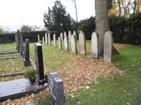 Teilansicht des jüdischen Friedhofs in Delmenhorst mit einer Reihe historischer Grabsteine und zeitgemäßen Grabstellen im Vordergrund.
