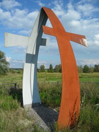 mehrere Meter hohes Kreuz aus Metallplatten, einseitig rostig, die einen Bogen bilden und jeweils ein Kreuz darstellen.